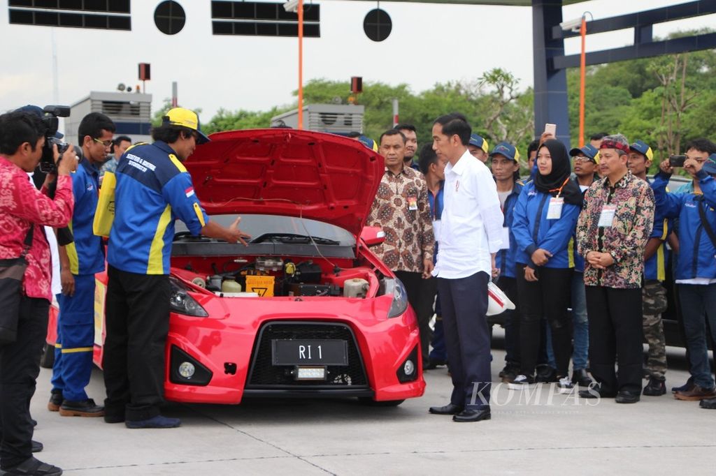 Presiden Joko Widodo melihat mesin dari mobil listrik Ezzy II seusai mencoba Tol Surabaya-Mojokerto di Gerbang Tol Warugunung, Surabaya, Jawa Timur, Selasa (19/12/2017).
