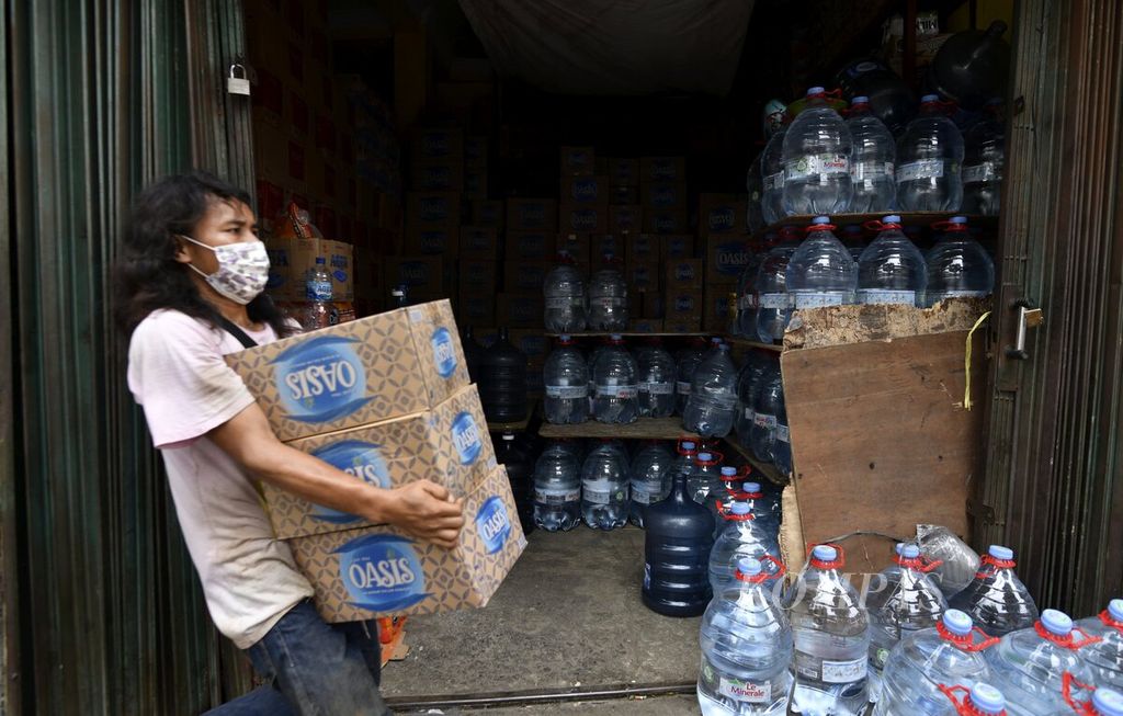 Pekerja membawa kardus berisi air minum dalam kemasan di salah satu toko di kawasan Manggarai, Jakarta Selatan, pertengahan Januari 2022. 