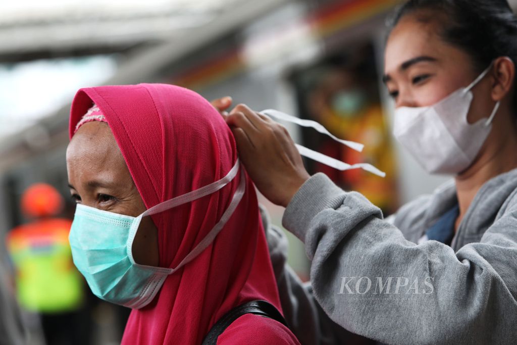 Calon penumpang kereta rel listrik (KRL) Commuterline memasangkan masker kepada penumpang lain di Stasiun Tanah Abang, Jakarta, Senin (3/2/2020). Masker tersebut dibagikan petugas KRL Commuterline secara gratis. Pembagian masker ini sebagai antisipasi dan respons terhadap penyebaran virus korona.