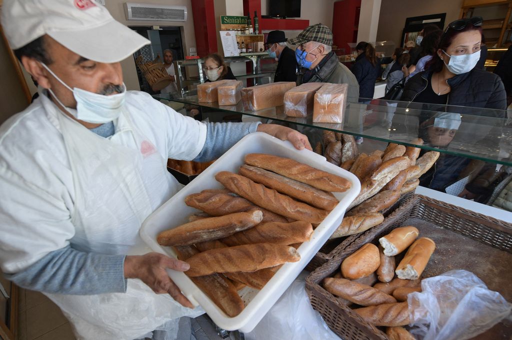 Pekerja membawa roti-roti segar yang baru saja dipanggang di sebuah toko roti di El Menzah, Tunis, Tunisia, 27 Februari 2022.  
