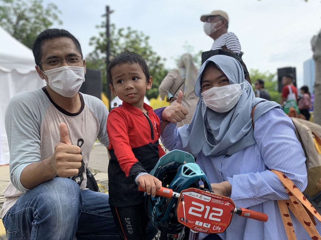 Dwinanto Adinugroho (42), Ihsan (2), dan Mahdewi Silky (41) sedang berpose saat ditemui seusai kompetisi balap sepeda tanpa pedal dalam acara Jakarta Sport Week di Plaza Timur GBK, Senayan, Jakarta, Minggu (13/11/2022). Menurut Mahadewi, kompetisi itu berdampak positif bagi anaknya.