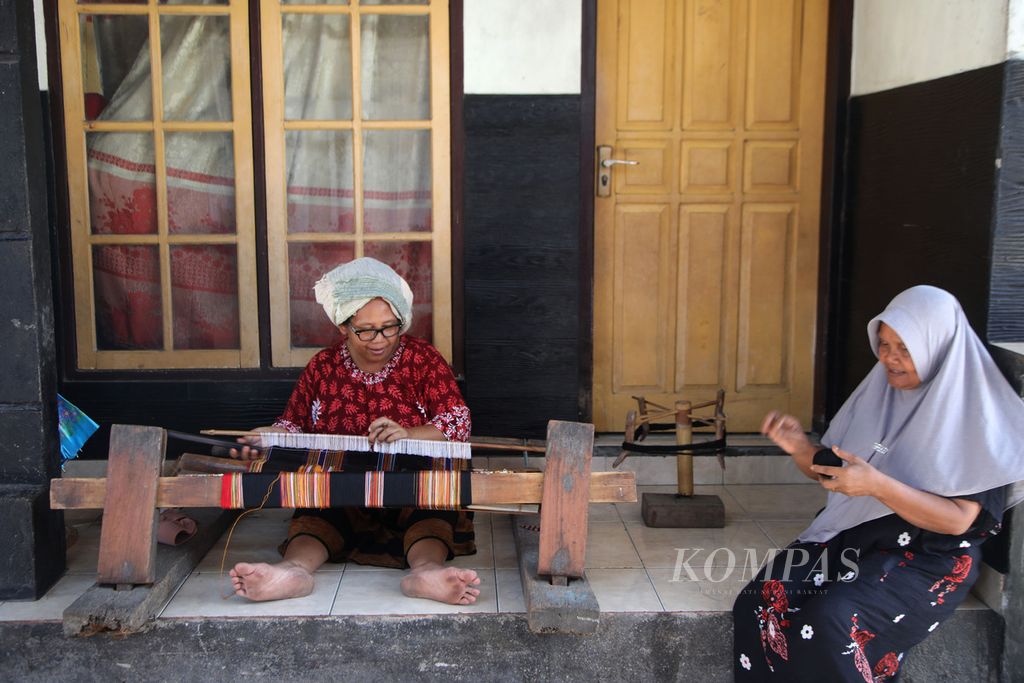 Ibu-ibu menenun di halaman rumah di Desa Pringgasela Selatan, Kecamatan Pringgasela, Kabupaten Lombok Timur, Nusa Tenggara Barat, Selasa (19/12/2023). Ada sekitar 700 petenun, sebagian besar ibu-ibu, di Pringgasela Selatan.  