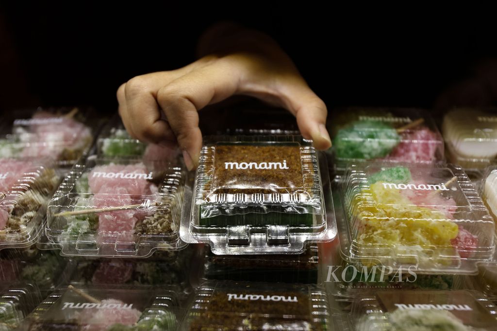 Tangan seorang pekerja menata makanan yang dijual di gerai Monami Bakery di Senayan City, Jakarta, Kamis (22/2/2024). Monami Bakery yang telah berdiri sejak 1976 sudah memasarkan jajanan pasar di mal sejak tahun 2012. 