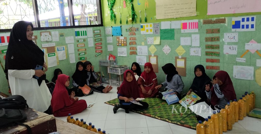 Guru di SDN 4 Akar-Akar, Kecamatan Bayan, Lombok Utara, Nusa Tenggara Barat, Rabu (17/5/2023), mendampingi para siswa membaca buku cerita bersama seusai pembelajaran.