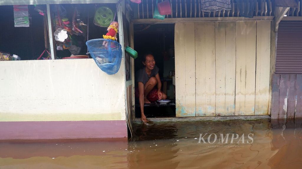 Seorang warga mencuci piring di beranda depan rumahnya di Kelurahan Sungai Lulut, Kecamatan Banjarmasin Timur, Kota Banjarmasin, Kalimantan Selatan, Minggu (24/1/2021). Hampir dua pekan permukiman warga di tepian Sungai Lulut, anak Sungai Martapura, itu dilanda banjir dan air belum juga surut.