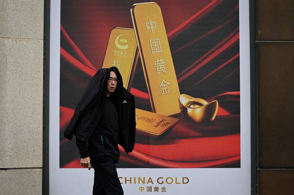 Seorang pria berjalan di depan papan iklan penjualan emas di Beijing, China, 10 April 2024. 