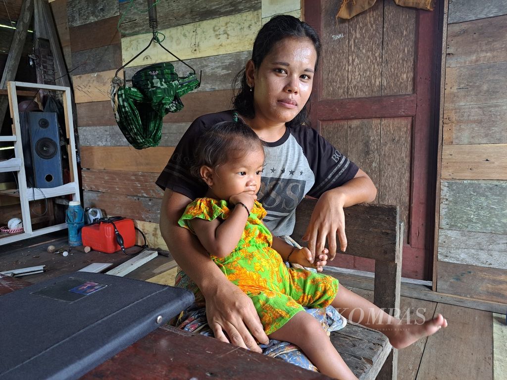 Wasnida Saogo tengah memangku putrinya, Riana, yang mengalami <i>stunting</i> atau tengkes di rumah mereka di Dusun Sinaka, Desa Sinaka, Kecamatan Pagai Selatan, Kepulauan Mentawai, Sumatera Barat, Sabtu (17/6/2023). 