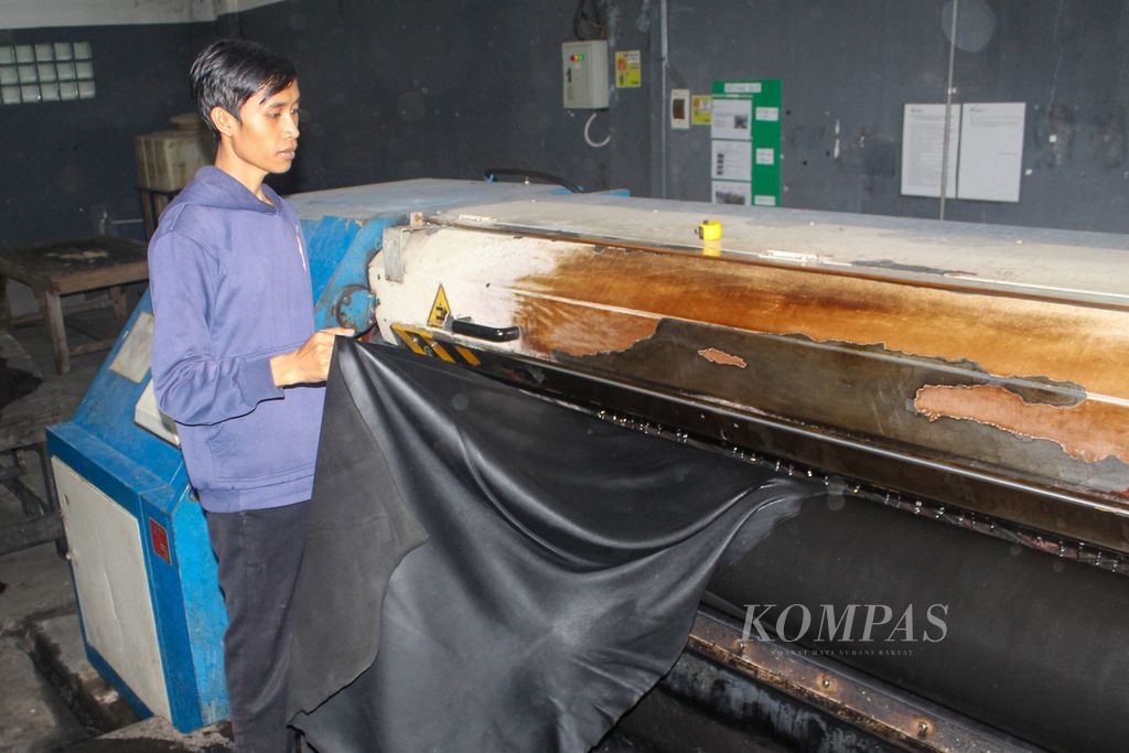 Salah seorang pekerja PT Garut Makmur Perkasa memasukkan kulit sapi yang telah diproses dengan campuran bahan minyak, warna, dan zat kimia ke dalam alat bernama <i>setting out</i>, Kamis (28/3/2024). 