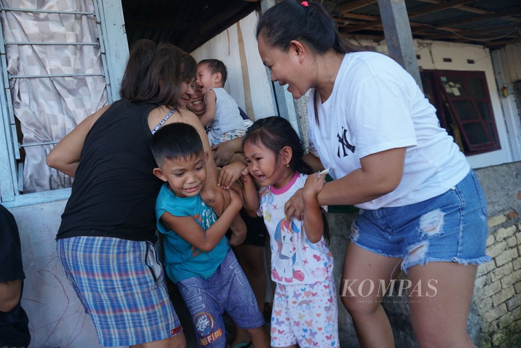 Para orangtua menakut-nakuti anaknya ketika sekelompok sinterklas dan piet hitam dari komunitas pemuda Second Family berkunjung ke permukiman mereka di bilangan Banjer, Manado, Sulawesi Utara, Minggu (11/12/2022).