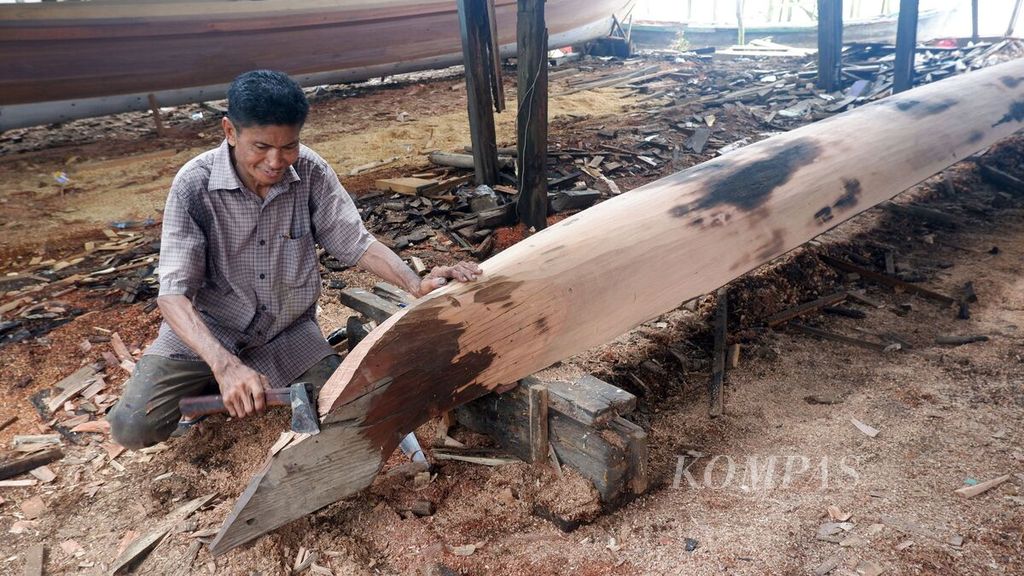 Seorang tukang menatah kayu dalam proses pembuatan lunas perahu di Desa Pulau Sewangi, Kecamatan Alalak, Kabupaten Barito Kuala, Kalimantan Selatan, Sabtu (9/3/2024).
