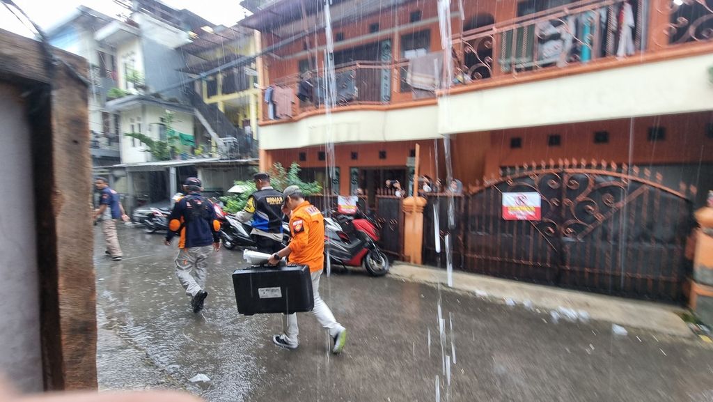 Sejumlah petugas kepolisian berlari menerobos hujan di RT 003, RW 001, Kelurahan Batununggal, Kecamatan Bandung Kidul, Kota Bandung, Jawa Barat, Selasa (13/12/2022). Para petugas ini melakukan penggeledahan di salah satu kamar kontrakan. 