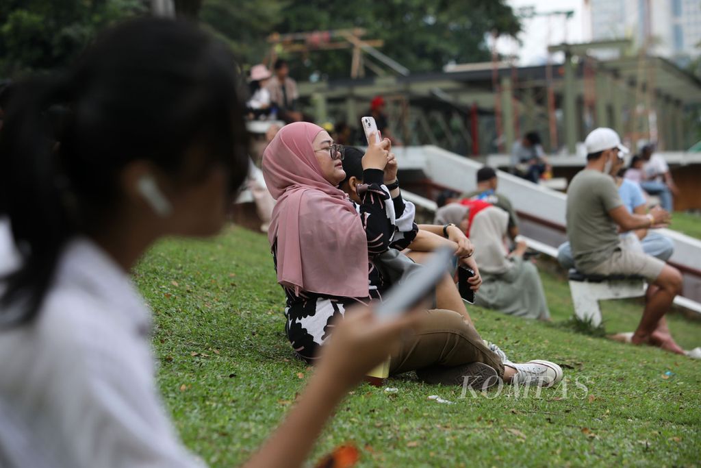 Warga bersantai sembari menikmati suasana sore di Hutan Kota Gelora Bung Karno, Jakarta, Minggu (25/6/2023). 