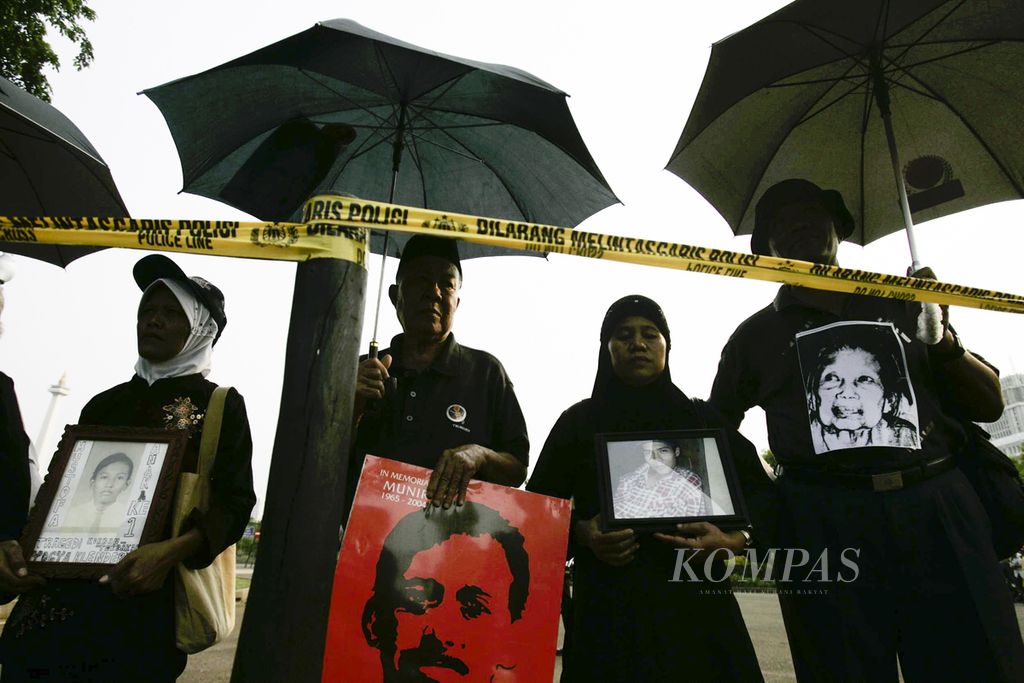 Pengunjuk rasa yang tergabung dalam Jaringan Solidaritas Keluarga Korban (JSKK) dalam aksi diam dengan membawa foto korban pelanggaran HAM dan payung hitam di depan Istana Merdeka, Jakarta, Kamis (18/1/2007). 