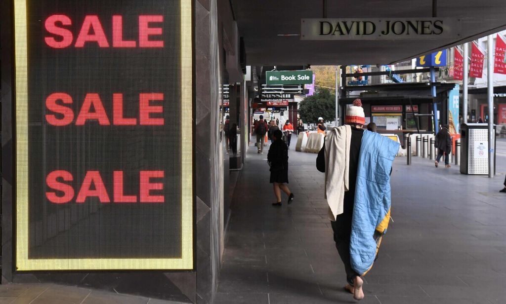 Tunawisma berjalan melewati tulisan penanda diskon di kawasan pusat bisnis Melbourne, 3 Juni 2020. 
