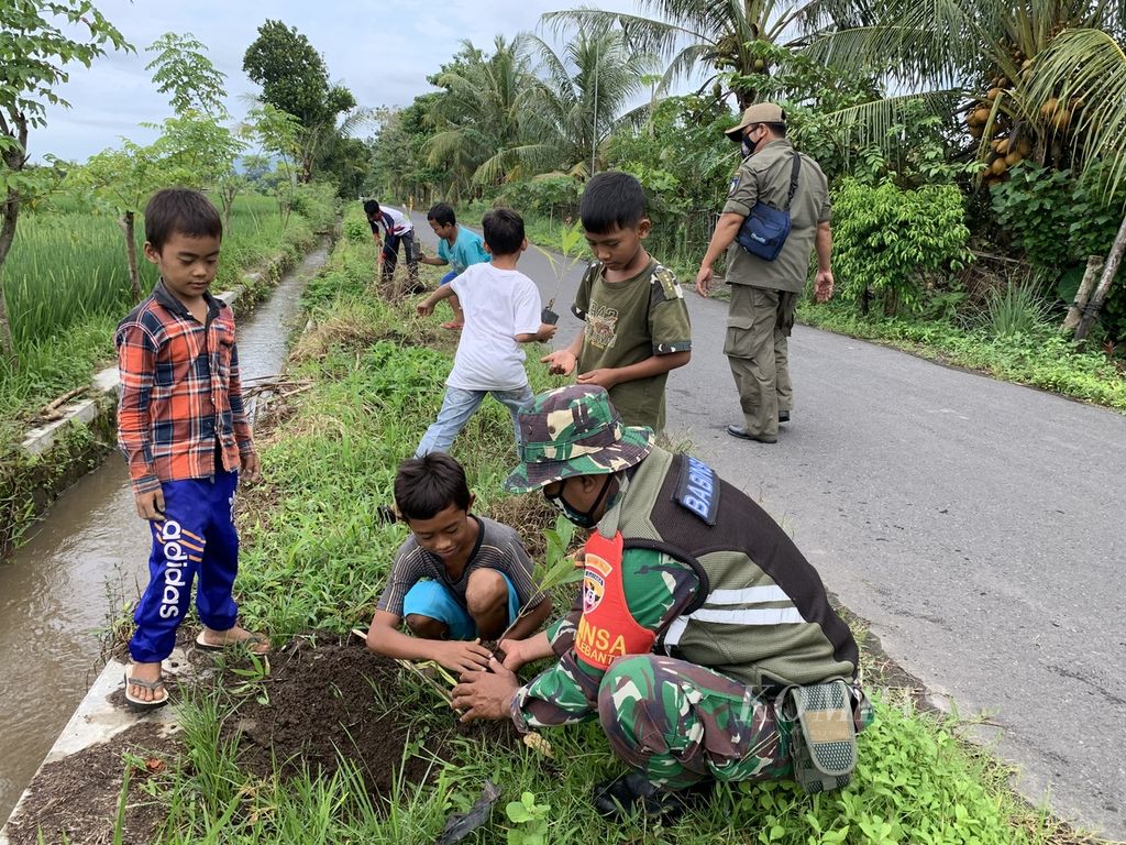 Anak-anak ikut mengambil bagian dalam gotong royong menanam pohon di pinggir jalan Desa Wisata Hijau Bilebante, Lombok Tengah, NTB, Jumat (12/2/2021).