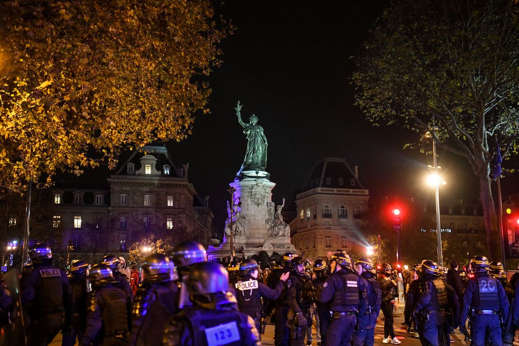 Petugas polisi berdiri di sela-sela demonstrasi yang menyerukan penampungan bagi para imigran di Place de la Republique di pusat kota Paris, Selasa (24/11/2020). 