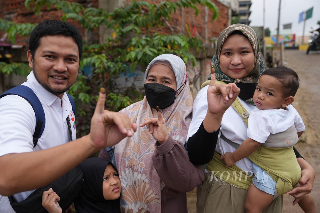 Risky (kiri) dan keluarganya menunjukkan jari yang telah dicelupkan tinta seusai menggunakan hak pilihnya dalam Pemilu 2024 di tempat pemungutan suara (TPS) di Kelurahan Cipinang Besar Utara, Jatinegara, Jakarta Timur, Rabu (14/2/2024). Berdasarkan hasil survei pascapecoblosan Pemilu 2024 oleh Litbang <i>Kompas</i>, 24,7 persen responden mengaku, anggota keluarganya masing-masing memiliki pilihan yang berbeda. 