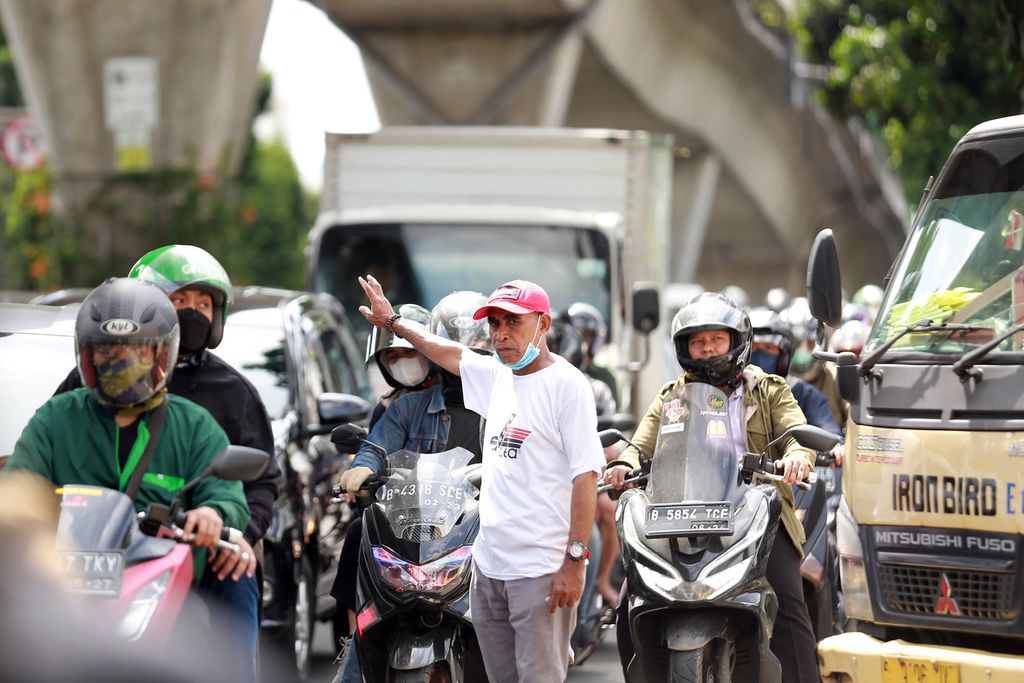 Salah seorang sukarelawan lalu lintas (polisi cepek) mengatur jalan, di Jalan Kapten Tendean, Jakarta Selatan, Senin (24/10/2022). 