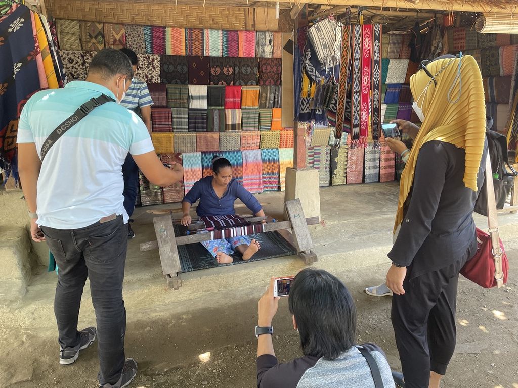 Pengunjung melihat kegiatan menenun yang dilakukan seorang warga di Desa Adat Sade, Rembitan, Kecamatan Pujut, Lombok Tengah, Nusa Tenggara Barat, Minggu (31/10/2021). Seiring semakin terkendalinya pandemi di Nusa Tenggara Barat, kunjungan wisata ke sejumlah kawasan wisata di Lombok mulai terlihat. 