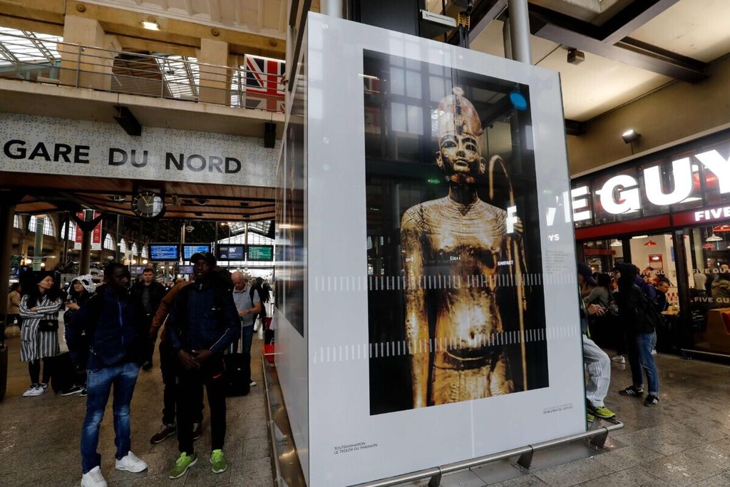 Warga berdiri disamping gambar ekshibisi "Tutankhamun, the Treasury of the Pharaoh", yang dipajang untuk publik di Gare du nord, Paris, Perancis, 12 Juni 2019.