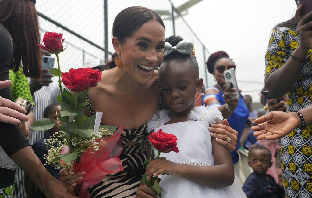 Meghan Markle (kiri) tersenyum saat menerima bunga pada pertandingan bola voli di Abuja, Nigeria, Sabtu, 11 Mei 2024. Pangeran Harry dan istrinya, Meghan, berada di Nigeria untuk mempromosikan Invictus Games yang ia dirikan untuk membantu rehabilitasi anggota militer dan veteran yang terluka dan cacat. 