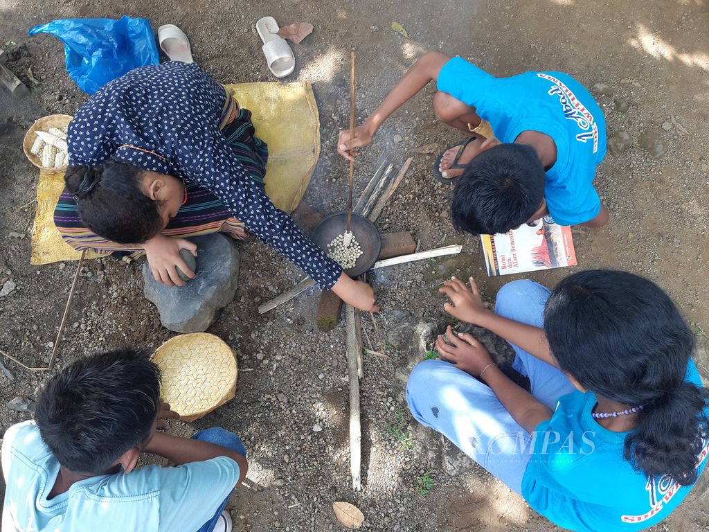 Para murid Sekolah Dasar Katolik Witihama di Pulau Adonara, Kabupaten Flores Timur, Nusa Tenggara Timur, bekerja sama memipih jagung di sekolah mereka pada Rabu (5/4/2023).