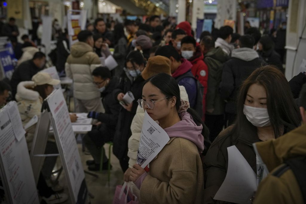 Pencari kerja memegang brosur saat mencari lowongan kerja di bursa kerja di Beijing, China, pada 23 Februari 2024. 