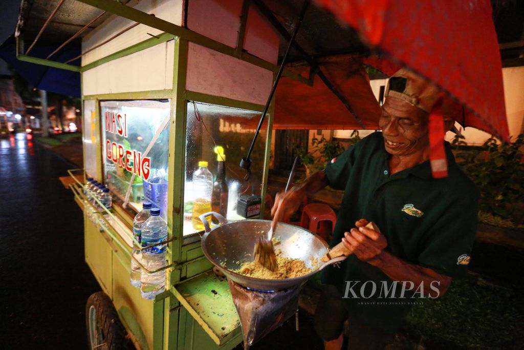 Pakde Joyo, pedagang nasi goreng dengan menggunakan gerobak saat mempersiapkan nasi goreng pesanan pembeli di kawasan perumahan Bintaro sektor 7, Tangerang Selatan, Banten, Rabu (12/10/2022) malam.