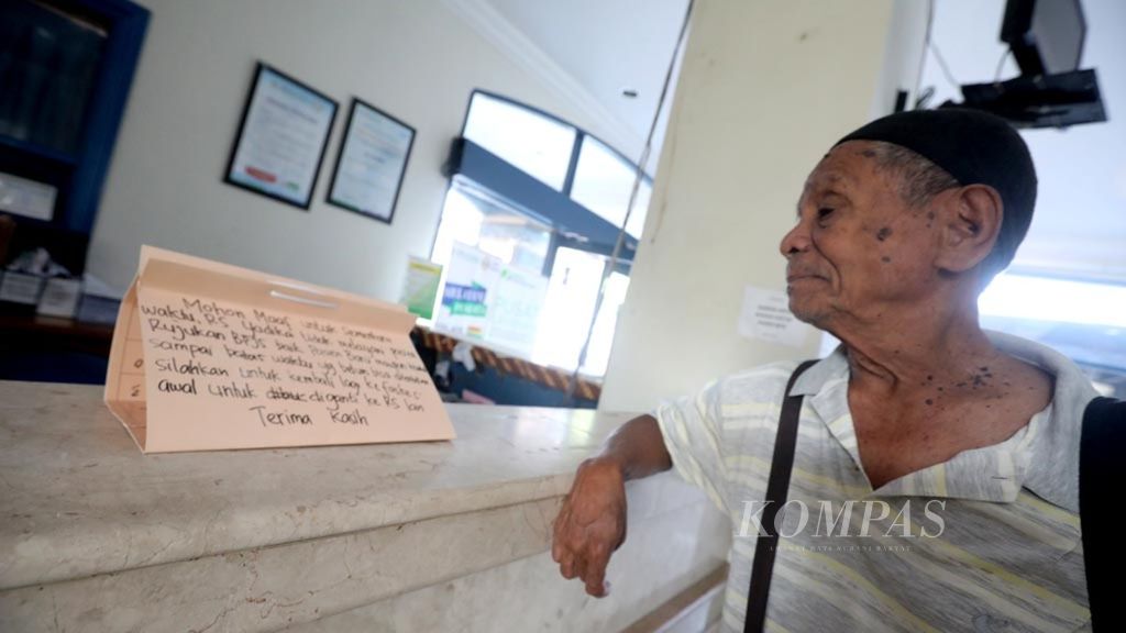 Pasien membaca keterangan yang dipasang di loket pendaftaran Rumah Sakit Yadika, Pondok Bambu, Jakarta Timur, yang menghentikan sementara pelayanan BPJS, Sabtu (6/1/2019). 