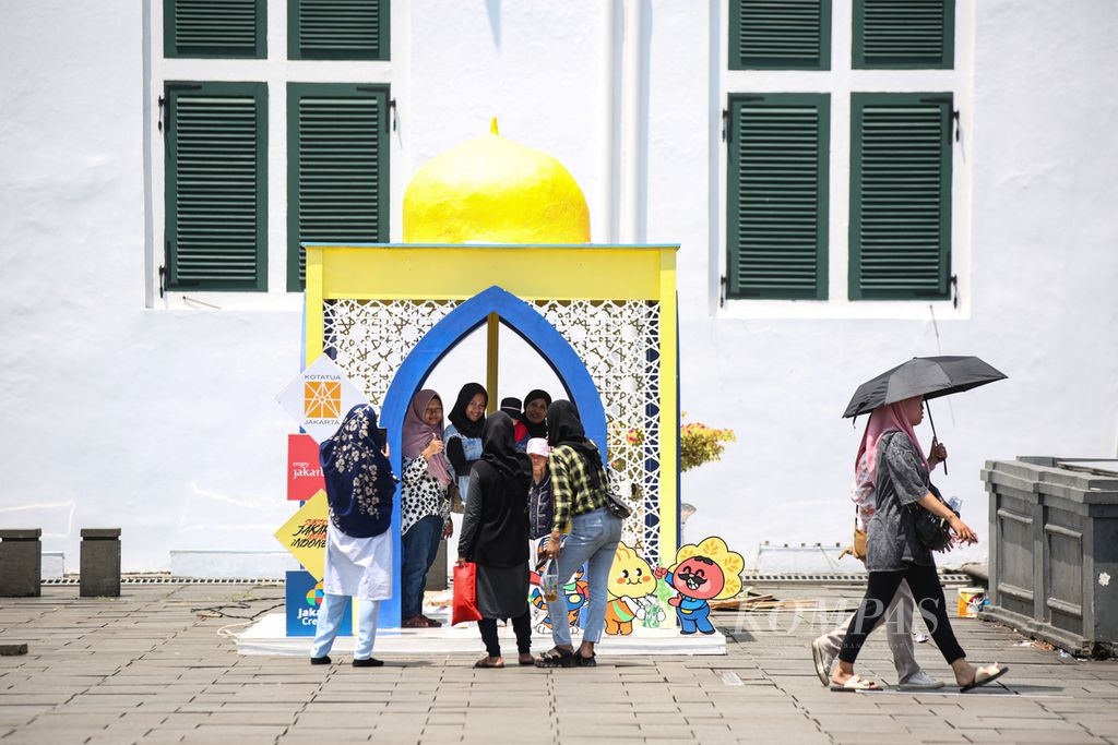 Pengunjung berfoto di dekorasi bernuansa Lebaran di Taman Fatahillah, kawasan wisata Kota Tua, Jakarta, Jumat (12/4/2024). Wisatawan yang berkunjung ke Kota Tua pada hari ketiga libur Lebaran ini didominasi oleh wisatawan domestik.