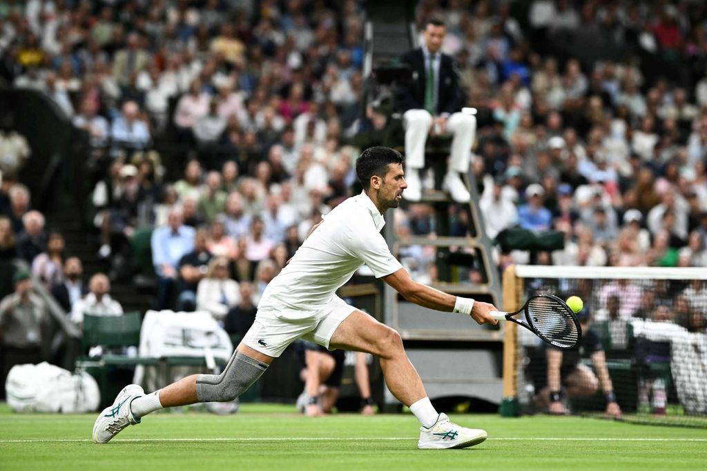 Petenis Serbia, Novak Djokovic, memukul bola ke arah petenis Denmark, Holger Rune, dalam pertandingan babak keempat turnamen Wimbledon di All England Club, London, Inggris, Senin (8/7/2024). Djokovic menang dengan skor 6-3, 6-4, 6-2.