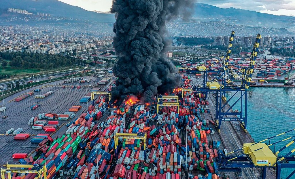 Dalam foto yang dirilis oleh agensi berita Turki, DHA (Demiroren News Agency), menunjukkan asap mengepul dari tumpukan kontainer yang porak-poranda dan terbakar di Pelabuhan Iskenderun di Hatay, Turki, sehari setelah gempa berkekuatan M 7,8 melanda bagian tenggara negara itu, Selasa (7/2/2023). 