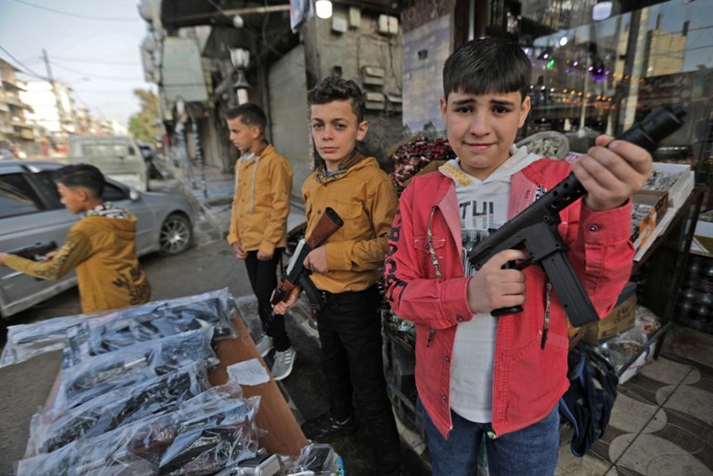 Bocah-bocah pria Suriah memegang senjata mainan dari plastik selama perayaan Idul Fitri, yang menandai berakhirnya bulan suci Ramadhan, dekat kota al-Bab, Suriah,  yang dikuasai Turki di pedesaan Aleppo, 2 Mei 2022 