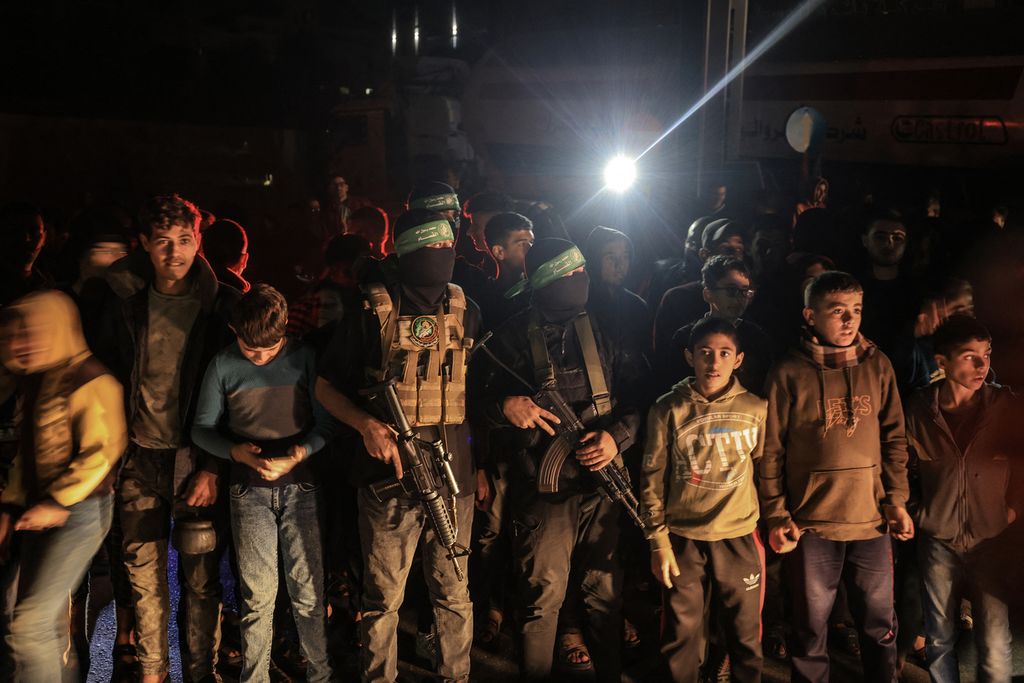 Anak-anak berdiri di dekat beberapa petempur Brigade Al-Qassam di Khan Yunis, Jalur Gaza selatan, 29 November 2023. 