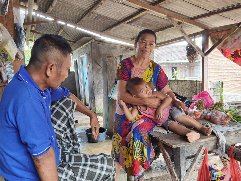 Bariah (50) dan Rustim (60) menemani cucu mereka, Farizi (2), di Dusun Mungkik, Desa Pandan Wangi, Kecamatan Jerowaru, Kabupaten Lombok Timur, Nusa Tenggara Barat, Rabu (3/3/2021). Pasangan itu saat ini harus merawat empat cucu yang masing-masing kedua orangtuanya menjadi pekerja migran.