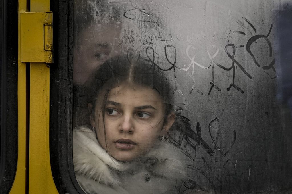 Seorang anak melihat keluar dari balik jendela bus yang berembunnsaat warga sipil dievakuasi dari Irpin, di pinggiran Kiev, Ukraina, Rabu (9/3/2022). Perang proksi antara Rusia melawan Amerika Serikat dan sekutu di Ukraina menyengsarakan rakyat negara itu. 