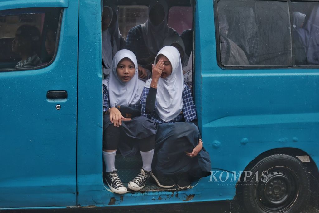 Siswi sebuah sekolah menengah pertama pulang sekolah naik angkutan kota (angkot) saat hujan deras mengguyur Ciampea, Bogor, Jawa Barat, Selasa (14/11/2023). 