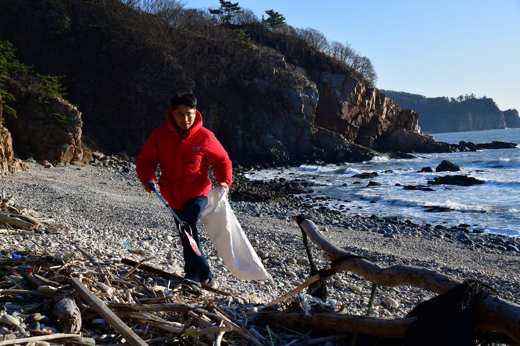 Kang Dong Wan memungut sampah-sampah dari Korea Utara di pantai Pulau Yeonpyeong, Korea Selatan, 21 Desember 2021.