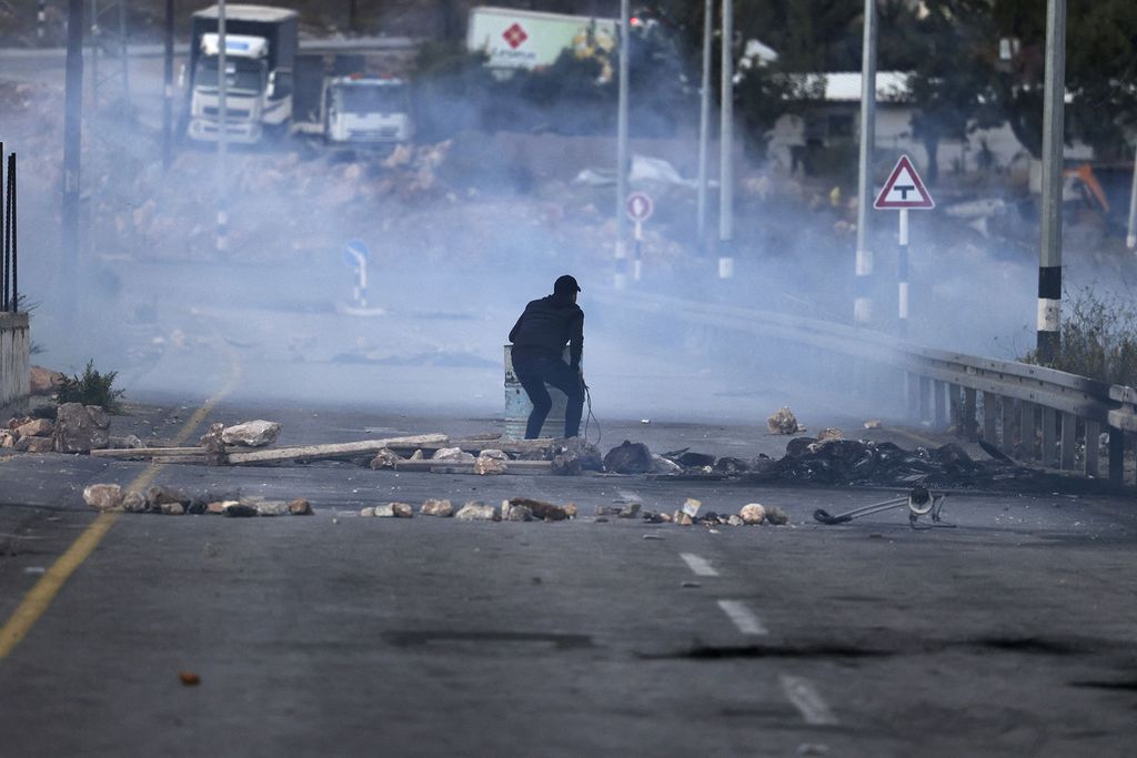 Seorang warga Palestina berdiri di tengah jalan yang menjadi area bentrokan antara warga Palestina dengan militer Israel di Ramallah, Tepi Barat, SElasa (25/10/2022). (Photo by Abbas MOMANI / AFP)