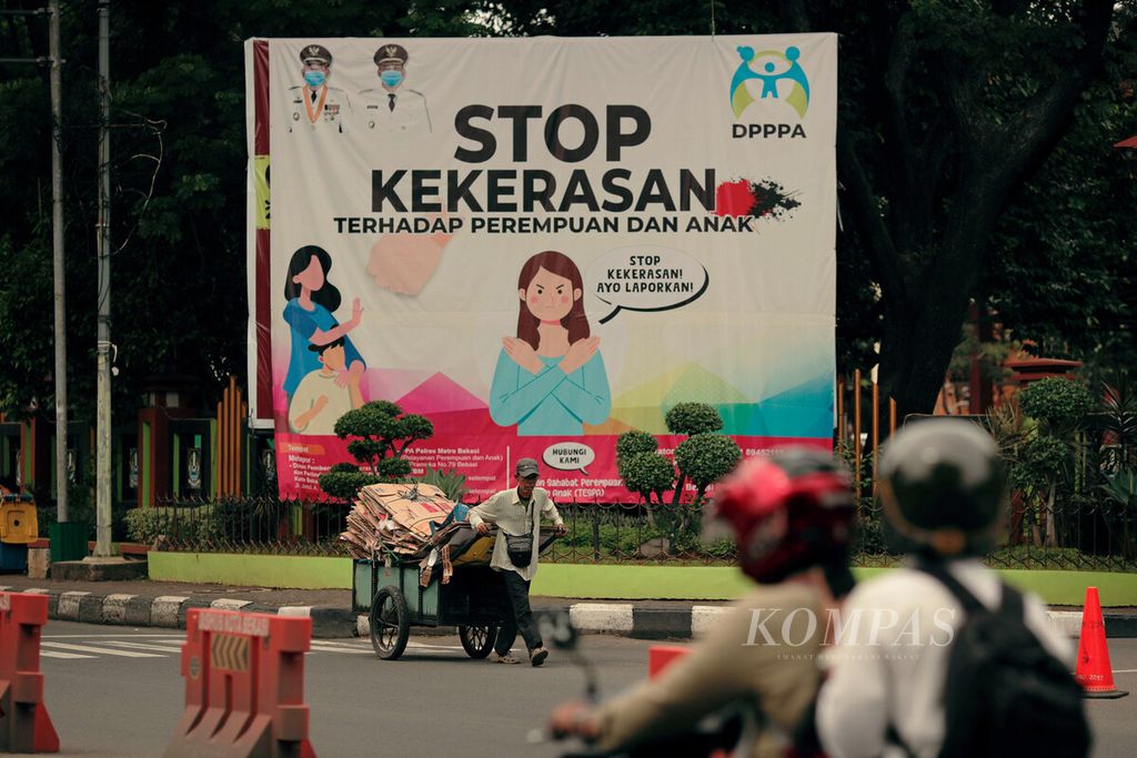 Warga melintasi baliho ajakan untuk menghentikan kekerasan terhadap perempuan dan anak di pintu masuk Kantor Wali Kota Bekasi, Jawa Barat, Rabu (23/6/2021). 