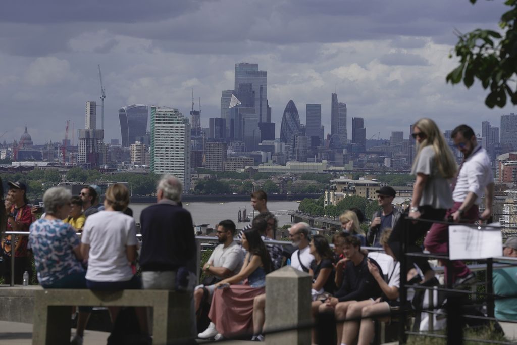 Warga duduk dengan pemandangan latar belakang berupa gedung-gedung pencakar langit di kawasan komersial di kota London, Inggris, 12 Juli 2023. 