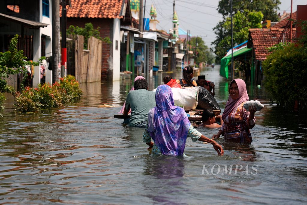 Warga melintasi genangan banjir saat akan menuju rumah mereka di Desa Wonoketingal, Kecamatan Karangtengah, Kabupaten Demak, Jawa Tengah, Kamis (15/2/2024). 